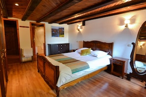 A bedroom with a wooden bed, a nightstand, a mirror, and a painting on the wall.