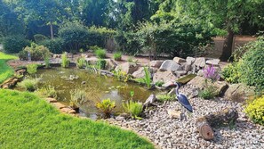 A garden with a pond, rocks, and a heron.