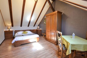 Ein Schlafzimmer mit einem hölzernen Bett, einem Schrank aus Holz, einem Tisch mit grüner Tischdecke und einem Stuhl.