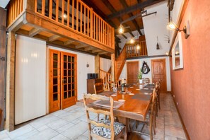 A dining area with a wooden table and chairs, a staircase, and a view of the kitchen.