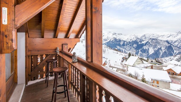 Een houten balkon met uitzicht op besneeuwde bergen.