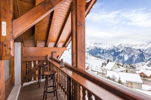 Een houten balkon met uitzicht op besneeuwde bergen.