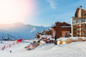 A ski resort with wooden buildings, a ski slope, and a mountain backdrop. - Hotel Bel Horizon by Skinetworks (Les Belleville)