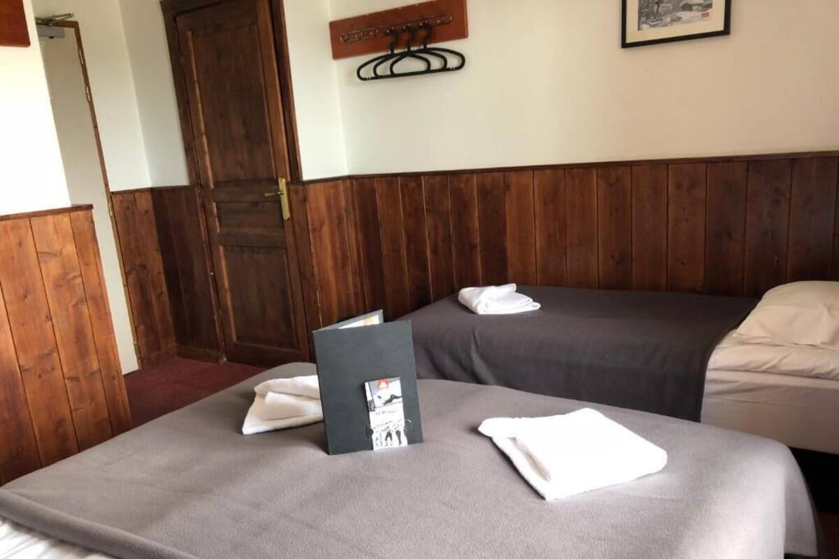 Ein Hotelzimmer mit zwei Betten, Holzvertäfelung, einer Tür und einem Kleiderständer.