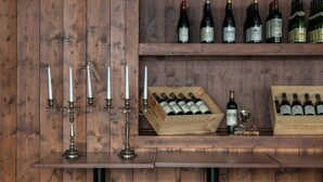A wooden bar with wine bottles and a candelabra. - Klubhotel Le Refuge by Skinetworks (Huez)
