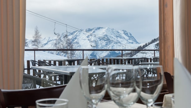 A restaurant with a mountain view, tables, and chairs. - Klubhotel Le Refuge by Skinetworks (Huez)