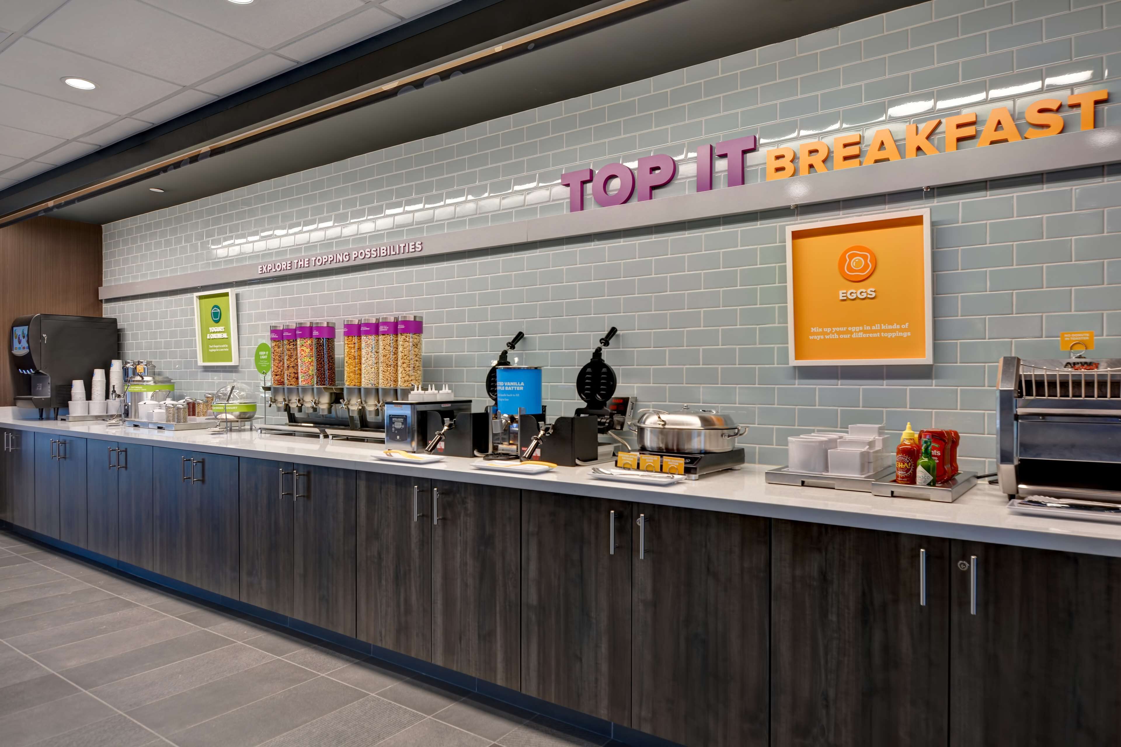 Aamiaispiste, jossa on kyltti, jossa lukee ”TOP IT BREAKFAST”, sekä erilaisia ruoka-aineita ja -tarvikkeita.