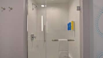 A modern bathroom with a glass-enclosed shower, a towel rack, and a shelf with toiletries.