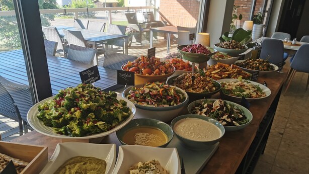 A buffet table with various dishes and a view of outdoor seating.