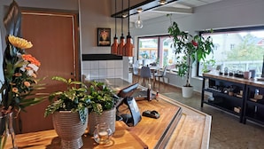 A modern kitchen with wooden countertops, potted plants, and hanging pendant lights.