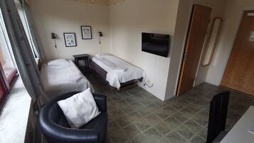 A room with two beds, a desk, a chair, a TV, and a mirror.