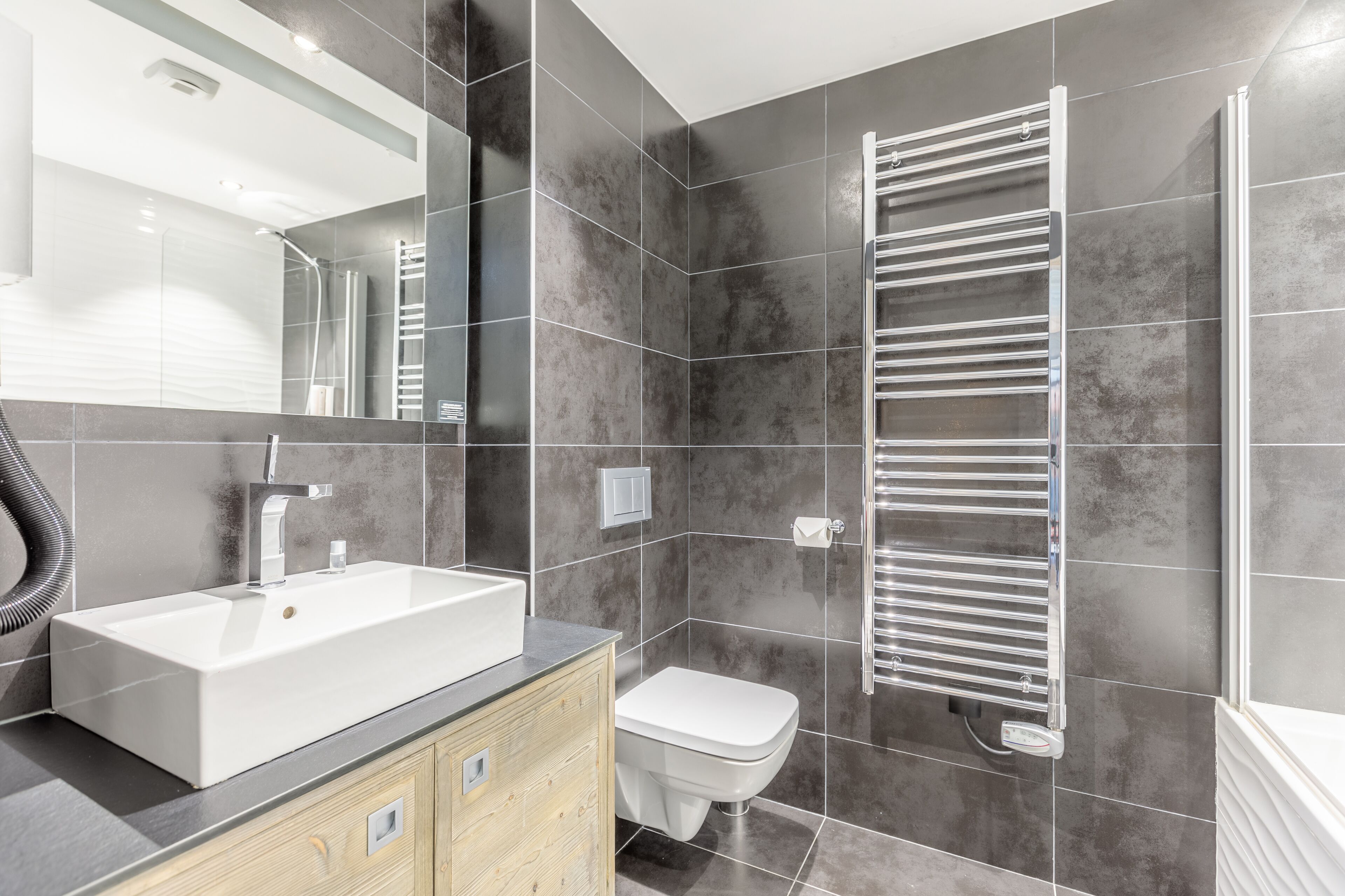 A modern bathroom with a large sink, a toilet, and a towel rack.