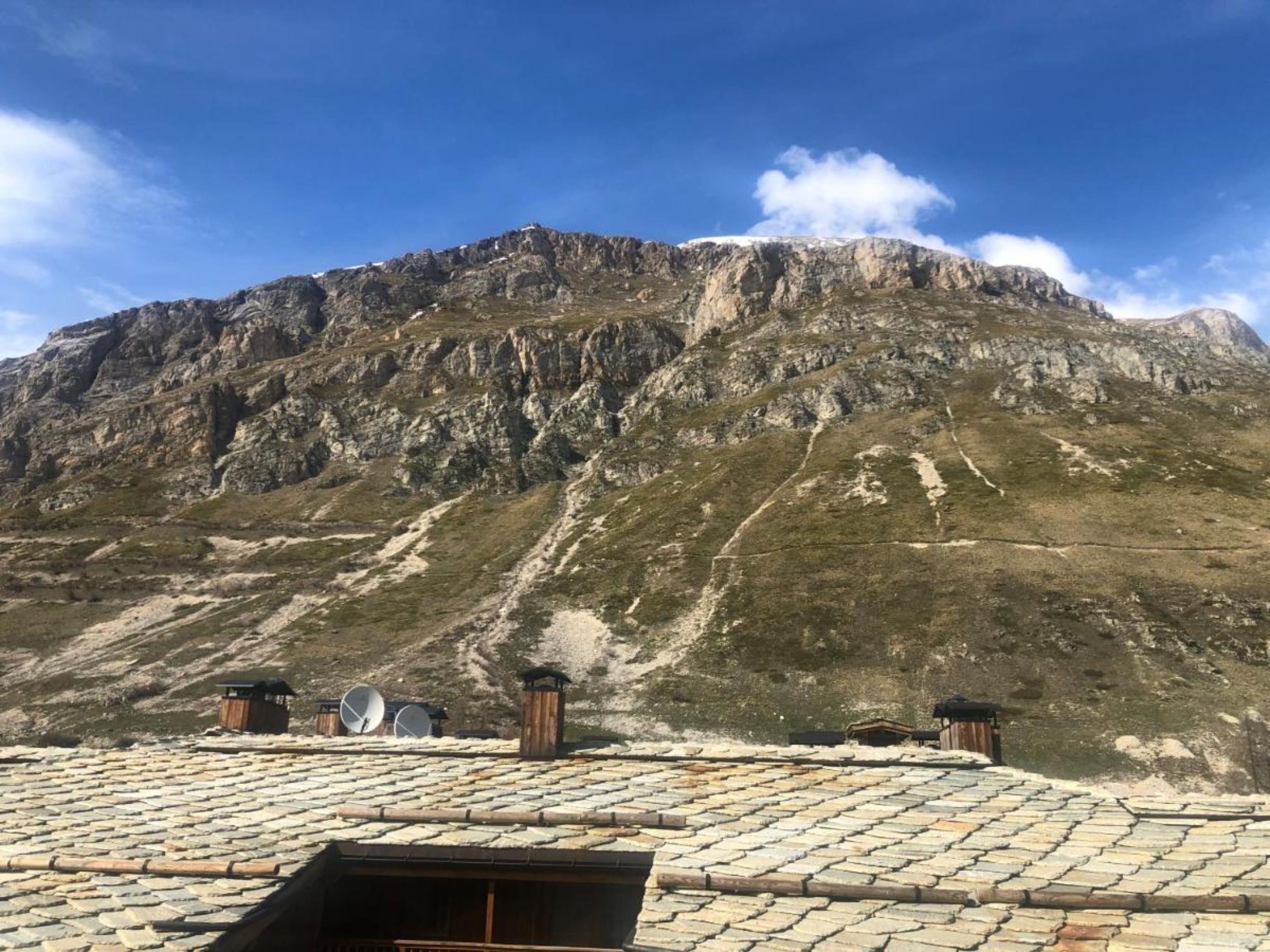 Un paisaje montañoso con tejado de piedra y un pequeño edificio con antenas parabólicas.