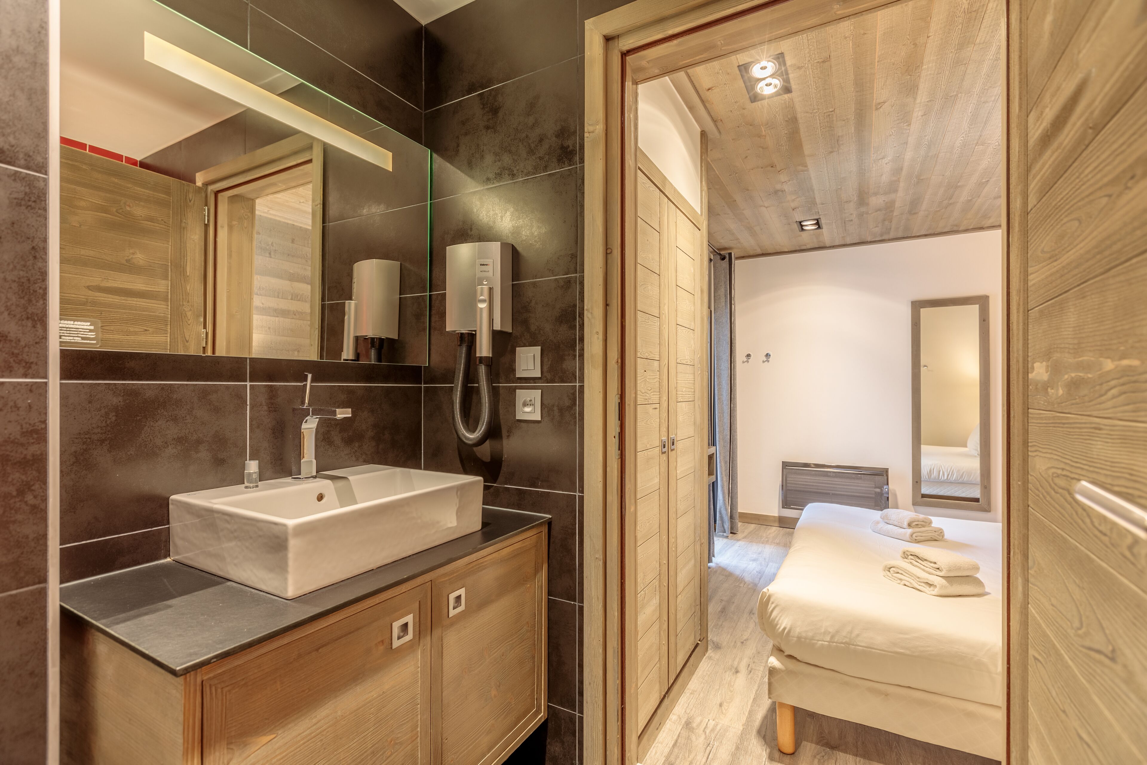 Un baño moderno con un espejo grande, un lavamanos y una zona de ducha.