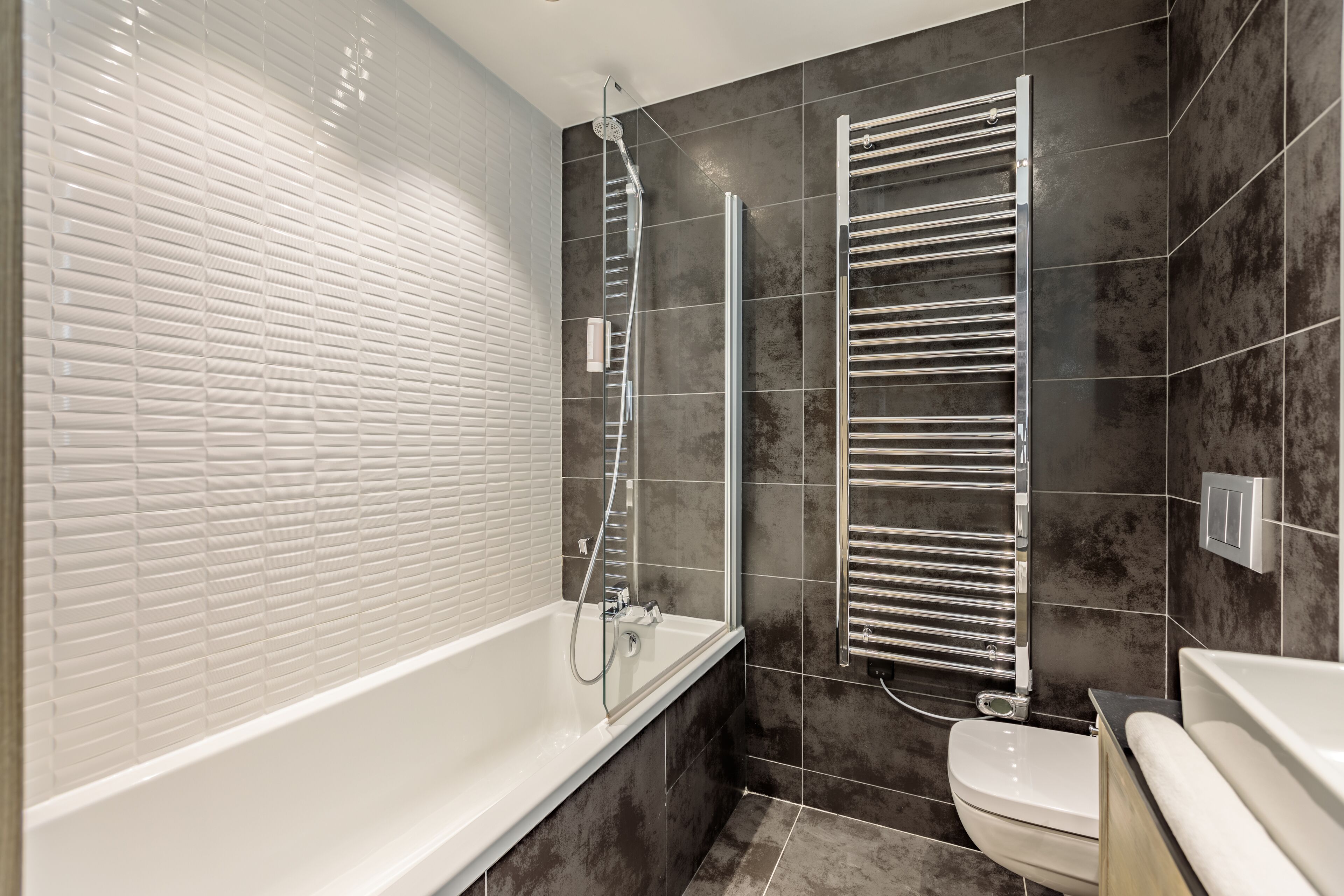A modern bathroom with a white bathtub, a toilet, and a shower area with a glass-enclosed shower.