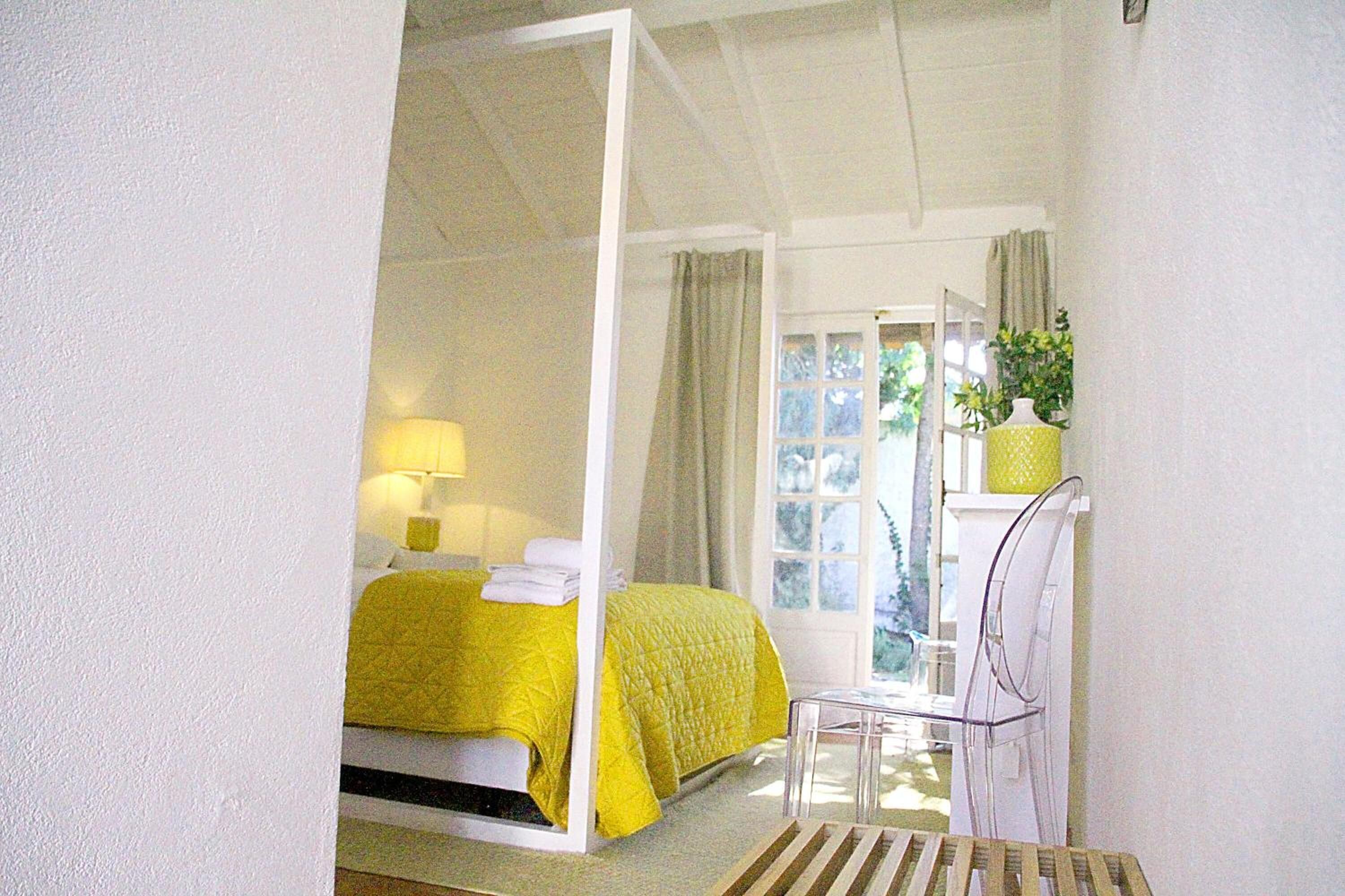 Une chambre avec un lit à baldaquin, une chaise, un bureau et une fenêtre avec des rideaux.