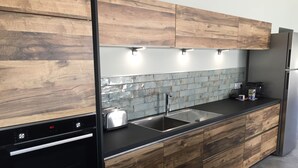 Eine moderne Küche mit Holzschränken, einer Edelstahlspüle, einem Toaster und einer Kaffeemaschine.
