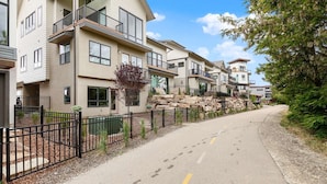 A residential street with modern houses, a paved road, and a stone wall.