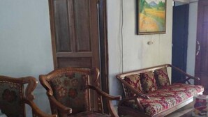 A living room with a wooden sofa, a matching armchair, and a coffee table with a floral design.