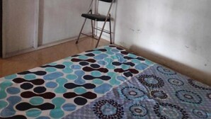A small room with a bed, a chair, and a wardrobe.