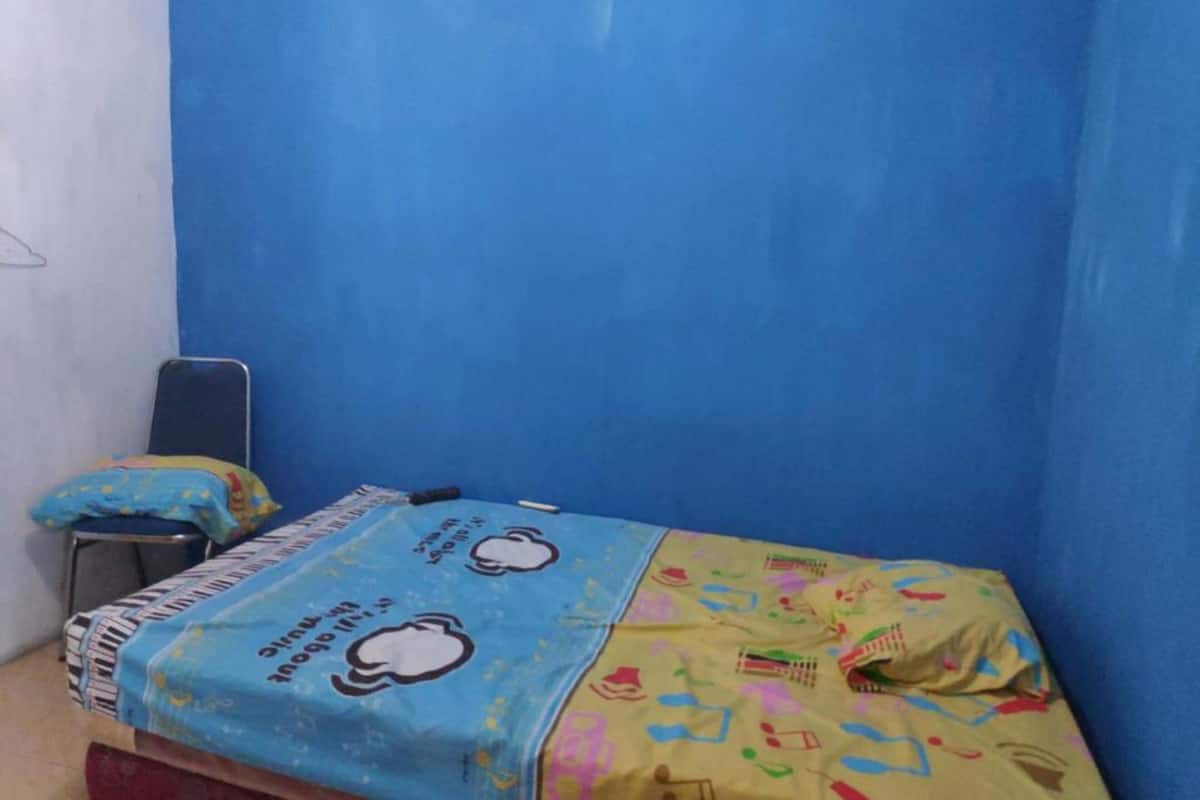 Una habitación pequeña con una cama individual, pared azul y una colcha azul y amarilla.