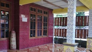 A covered outdoor area with a tiled floor, a pink bicycle, and a pillar with a patterned design.