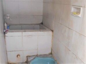 A small, tiled bathroom with a toilet, a sink, and a shower area. - Sardi Homestay (Imogiri)