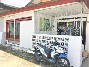 Een Honda scooter geparkeerd voor een gebouw met een witte gevel, een metalen poort en een raam met een groene omlijsting.