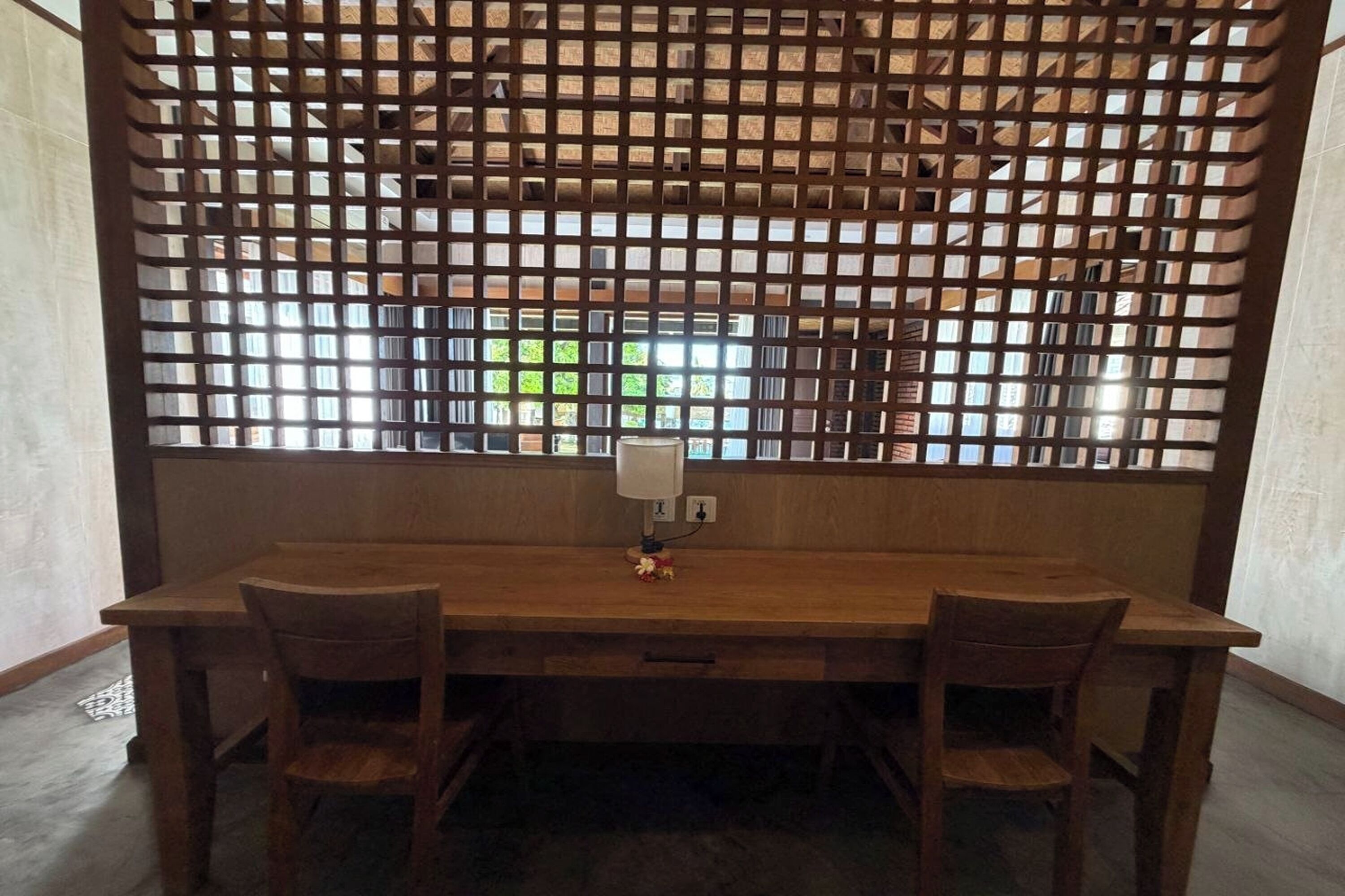 Una mesa de comedor de madera con dos sillas, un panel decorativo de madera y una ventana con vistas a zonas verdes.