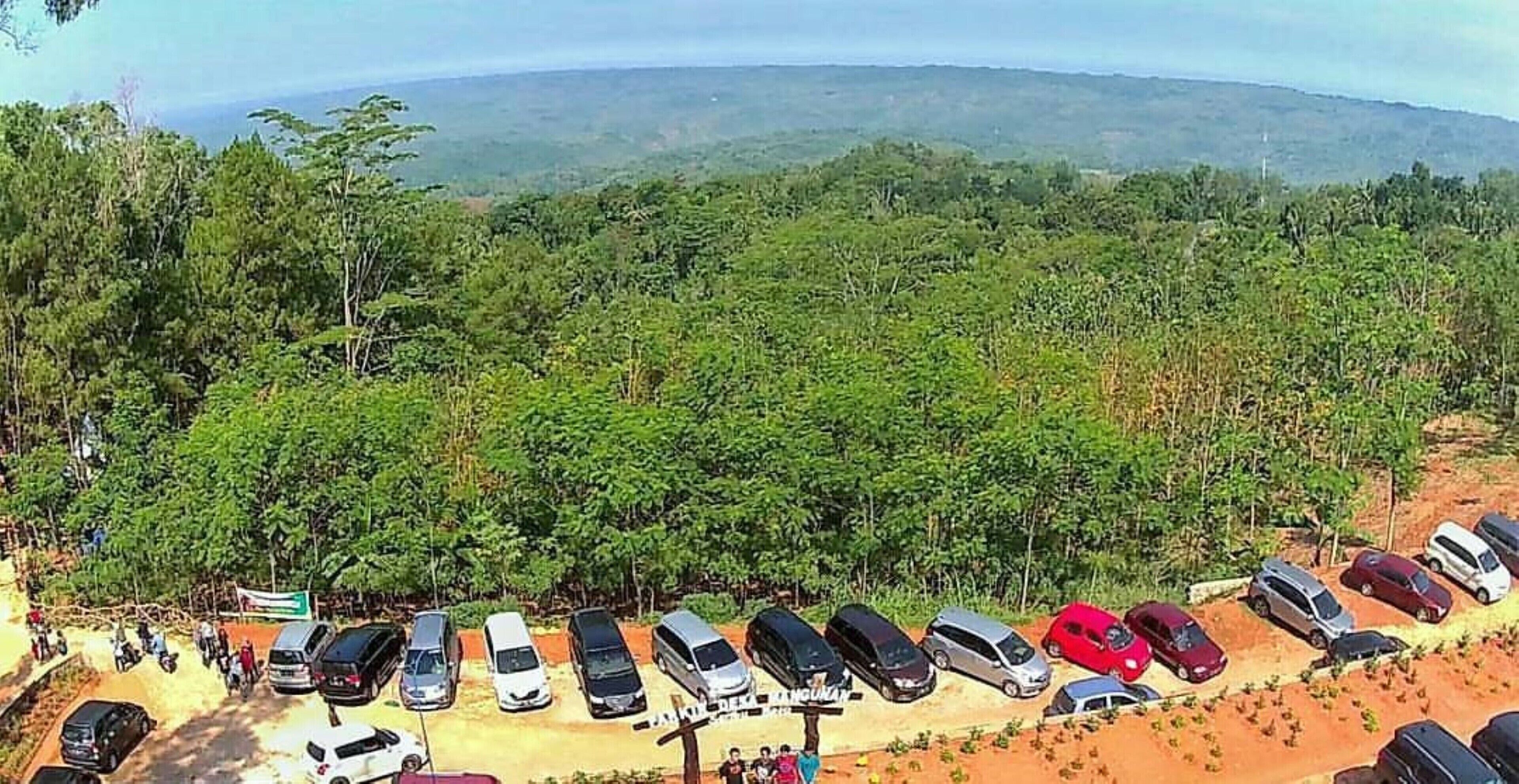 A parking area with multiple cars and a signboard.