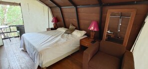 Un dormitorio con cama, lámparas de noche, una silla y una puerta.
