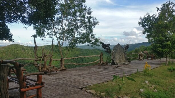 A wooden boardwalk with a rustic fence, surrounded by lush greenery and trees. - Watu Mabur Holiday Centre and Camping (Mangunan)