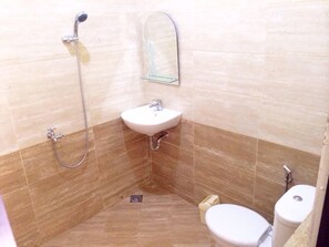 A bathroom with a shower, sink, toilet, and a mirror. - Homestay Griya Indah (Makassar)