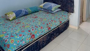 Un lit simple avec une couvre-lit à motifs floraux, une tête de lit et deux oreillers.