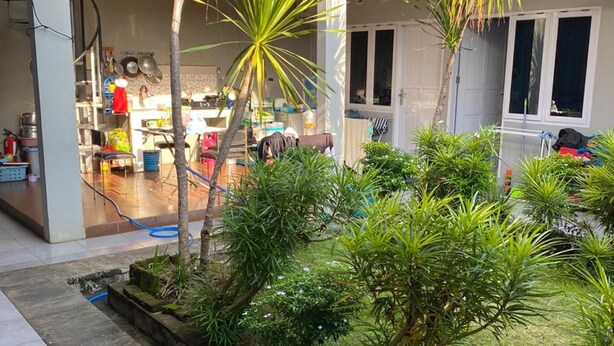 Une cour avec un petit jardin, un chemin pavé et un bâtiment doté d’un balcon.