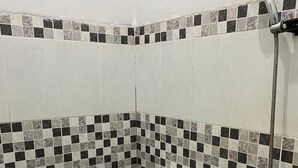 Une salle de bain avec des toilettes, une douche et des murs carrelés.