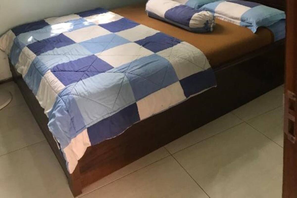 A bedroom with a bed, a headboard, and a window with curtains.