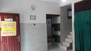 A room with a tiled floor, a red door, a green curtain, and a sign advertising a homestay. - Homestay Mas Arjuna - Female Only (Surabaya)
