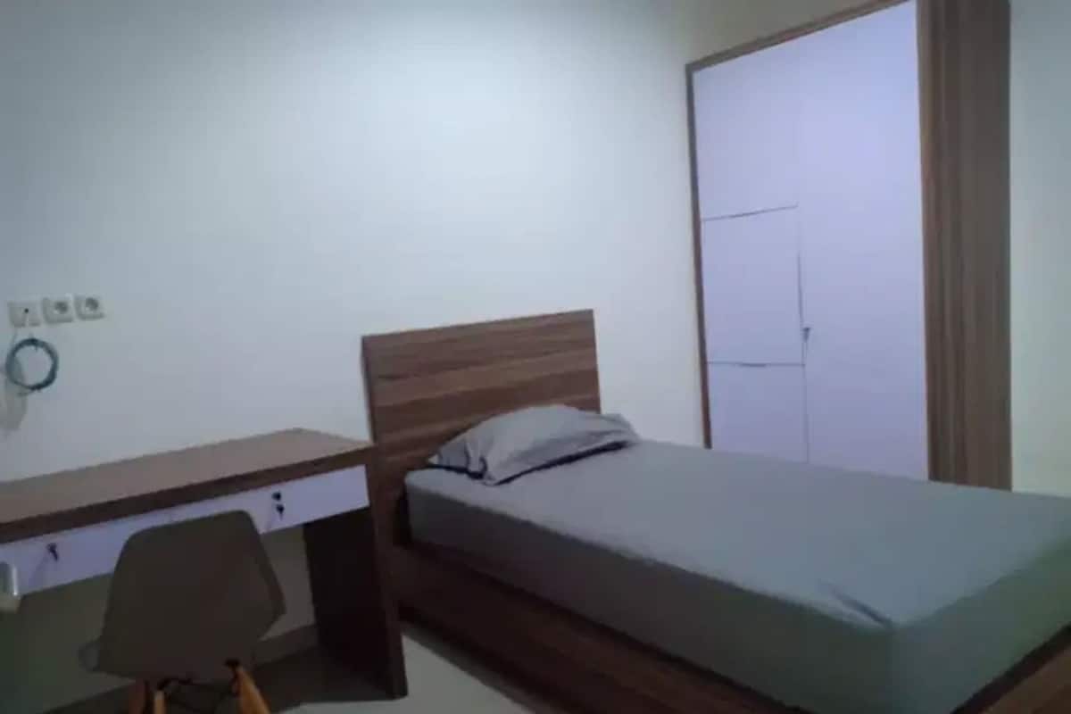 Un dormitorio con una cama de madera, un escritorio con silla y un armario.
