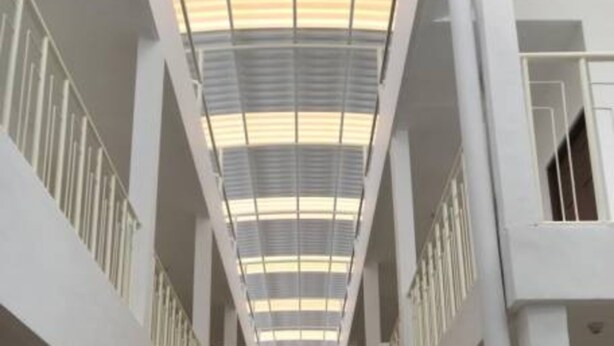 A spacious interior with a high ceiling and a central skylight, featuring a symmetrical layout with multiple doors and a clean, modern design. - Kost Harian 86 (Surabaya)