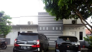 Two parked cars in front of a building with a modern design, including a staircase and a door with a window. - Dedy Kost (Jambi)