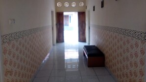 A hallway with patterned walls, a bench, and a door at the end. - Dedy Kost (Jambi)