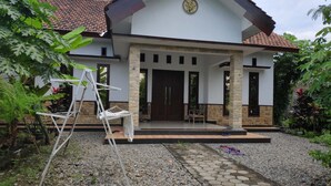 A house with a tiled roof, a front porch, and a stone pillar. - Dwi Sigit Homestay (Imogiri)
