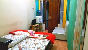 Un dormitorio con una cama, un escritorio con computadora, un dispensador de agua y una silla.