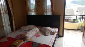 Un dormitorio con cama, colcha floral y cortinas.