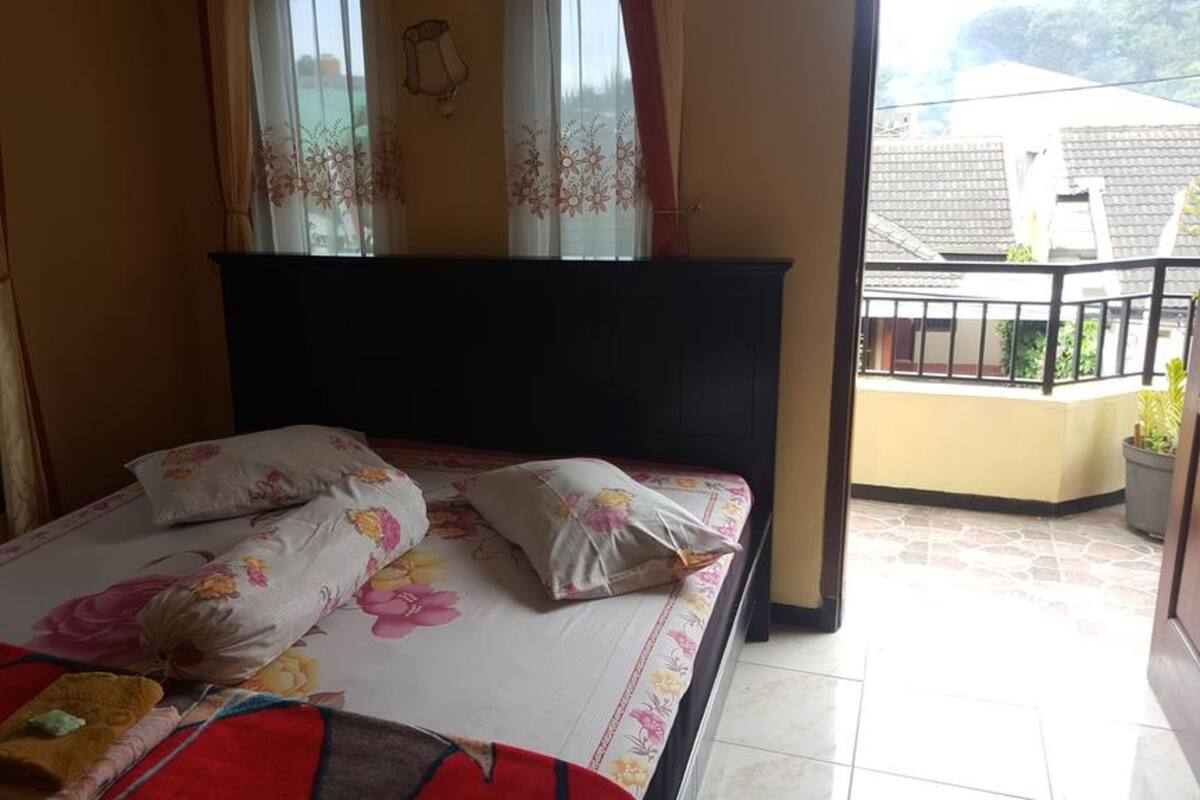 A bedroom with a bed, floral bedspread, and curtains.
