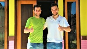 Two individuals standing in front of a yellow building with wooden doors and windows. - Fida Ijen Crater Guesthouse (Banyuwangi)