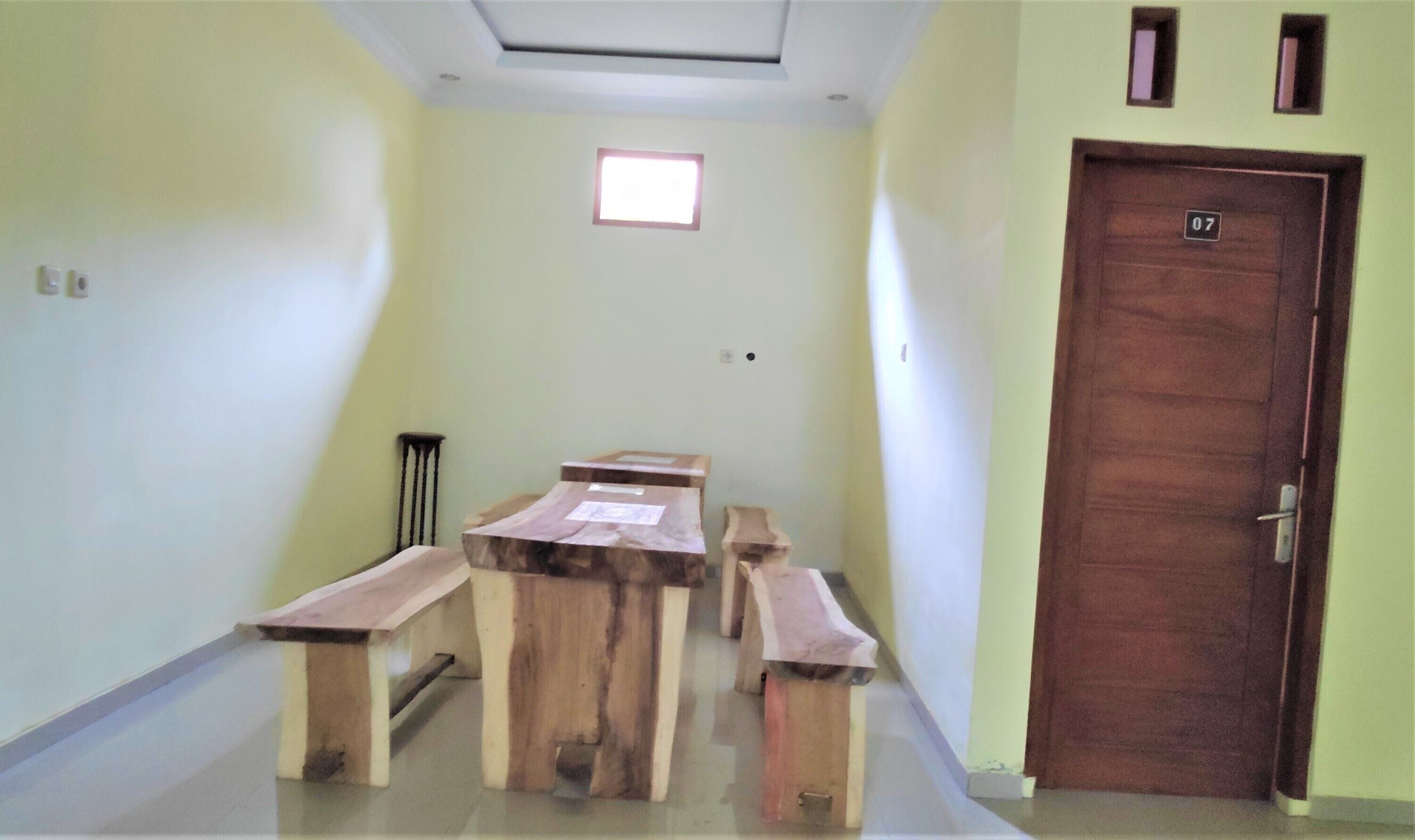 A hallway with a wooden bench table, a door marked with the number 07, and a small window.