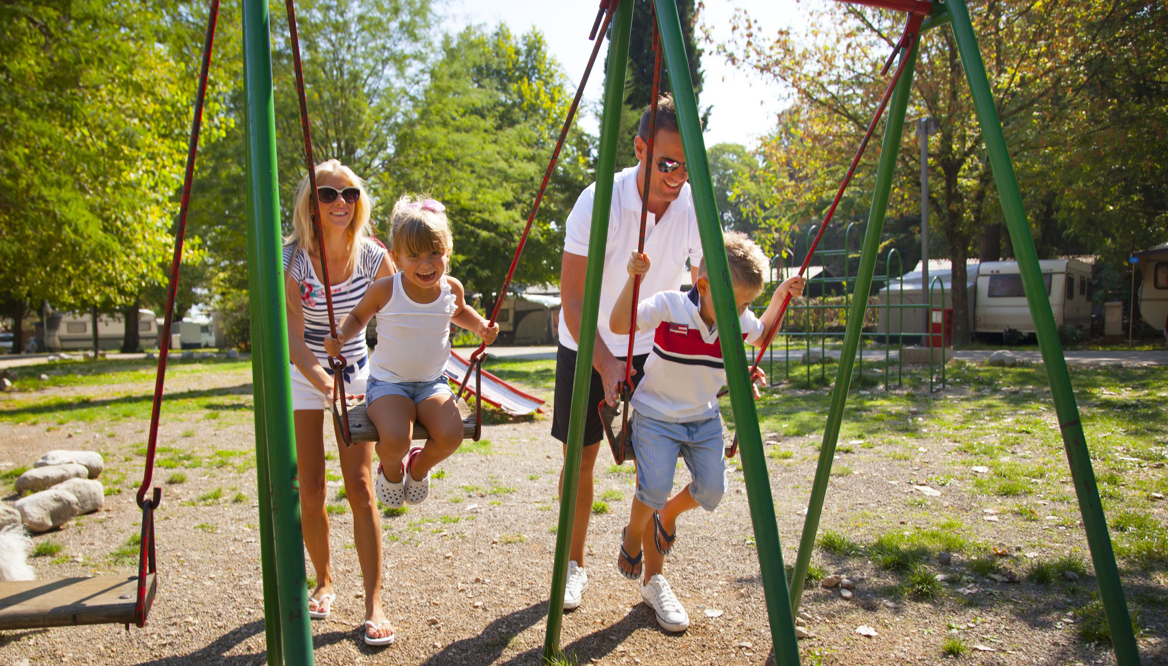 Un parque infantil con columpios y suelo de tierra.