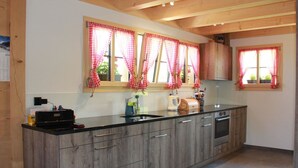 Una cocina con armarios de madera, encimera negra y cortinas a cuadros.